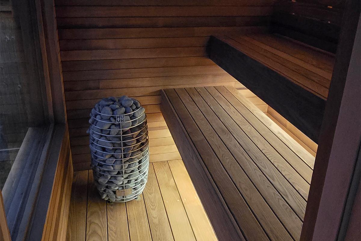 Ember Cabin interior showing two bench levels, a HUUM electric heater and wood flooring.