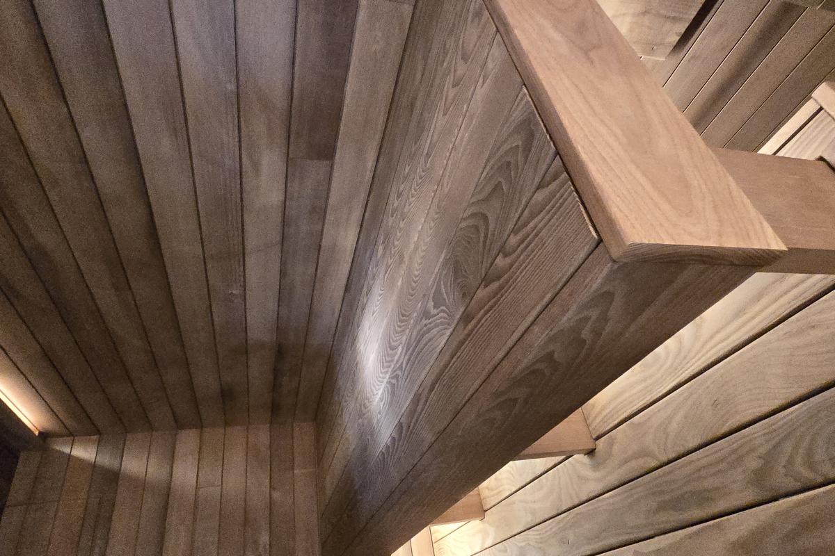 Close-up of the upper and lower wood benches and illuminated backrest in a Turon indoor sauna.