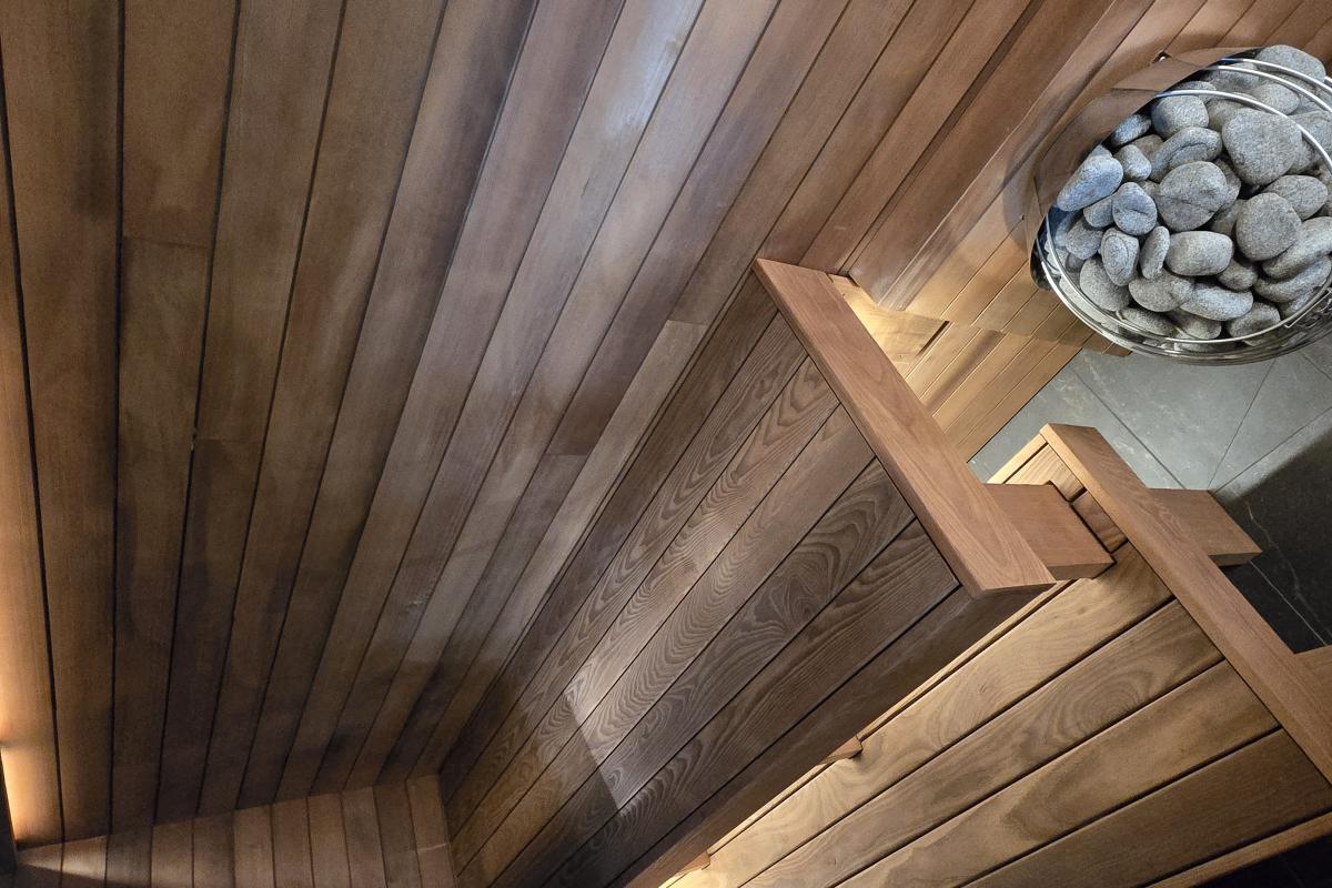 Interior of a completed Turon indoor sauna with wood benches, warm lighting and an electric sauna heater.
