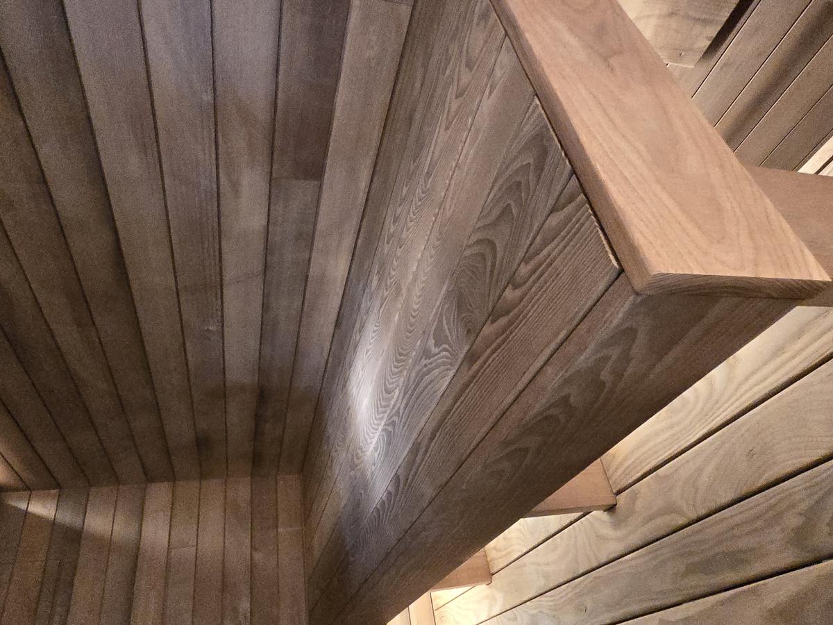 Close-up of the upper and lower wood benches and illuminated backrest in a Turon indoor sauna.