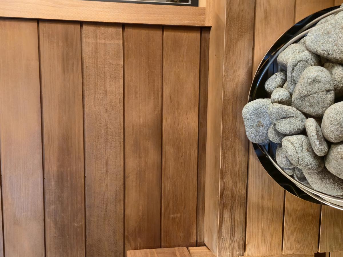 Sauna stones inside an electric heater against the wood-lined wall of a Turon indoor sauna.