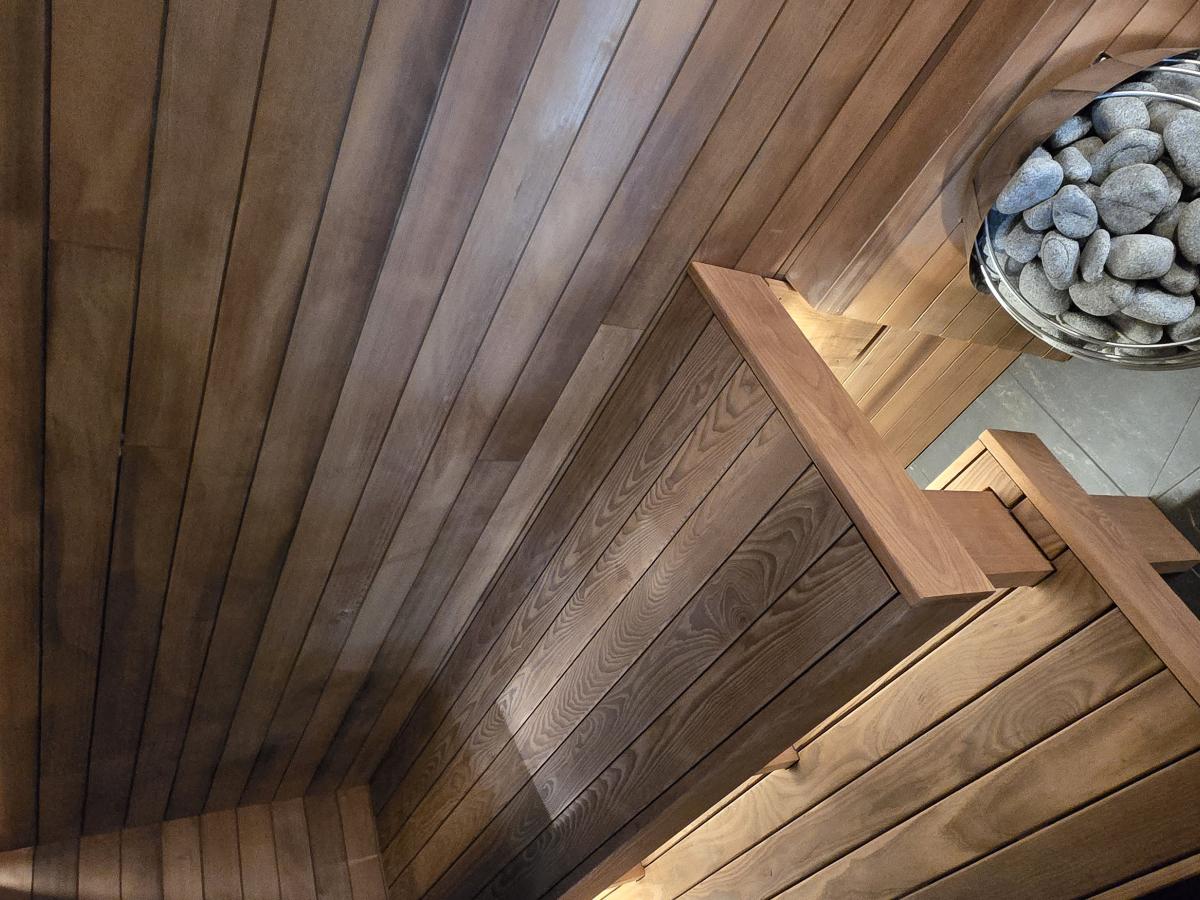 Interior of a completed Turon indoor sauna with wood benches, warm lighting and an electric sauna heater.